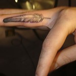 delicate shaded feather on finger by Majestic Tattoo