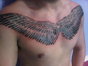 latin text wing chest tattoo by Adal at Majestic